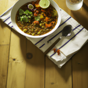 Caril de lentilha e vegetais (Vegan), luz quente, servido sobre mesa de madeira, talheres,